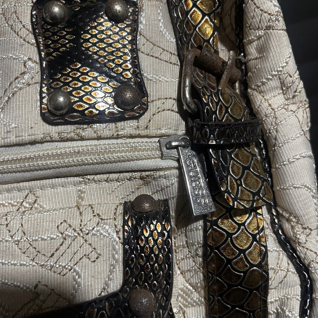 Guess beige and metallic snakeskin pattern handbag (Category: Luxury Bags & Wallets) located in Manila. Submitted by thrifted4life (Listing ID 1467536987, Image 3). Description: - Brand: Guess - Material: Cream embroidered monogram canvas with metallic gold-black snakeskin trim - Hardware: Silver-tone with branded zipper pull - Storage: Dual straps, structured bottom with metal feet, front zippered compartment, and front flap pocket - Perfect sta