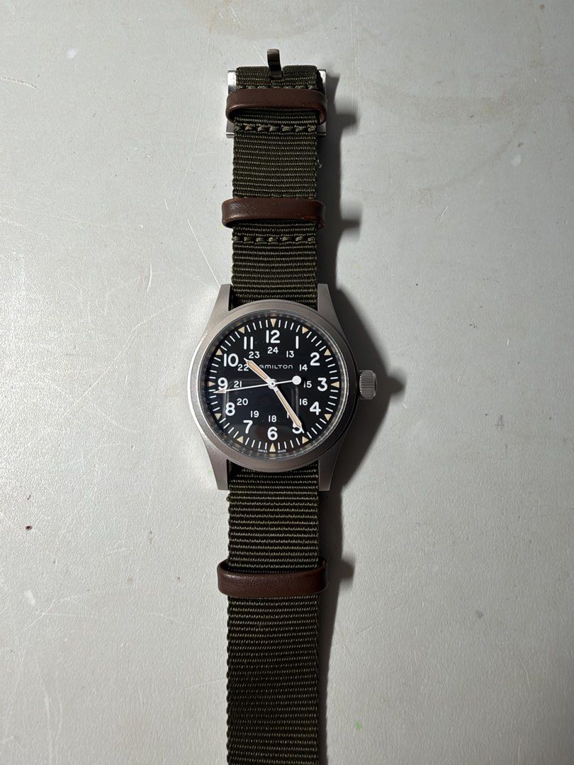 Hamilton Khaki Field Mechanical Watch H694390 (Category: Men's Watches) located in Manila. Submitted by red.014 (Listing ID 1467531437, Image 2). Description: - Brand/Model: Hamilton Khaki Field Mechanical (Ref. H694390) - Movement: Swiss manual wind, running great - Dial: Black with white numerals, 24-hour markings, and luminous markers - Case: Matte stainless steel with signed crown and clean crystal - Strap: Green nylon NATO strap with brown l