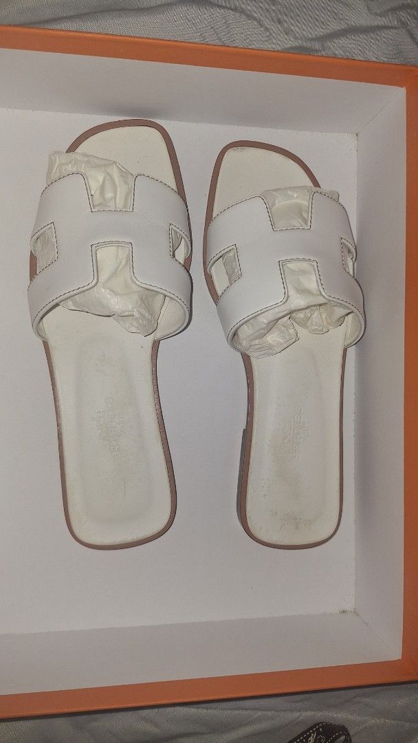 Hermes White Oran Sandals Size 35 (Category: Flats & Sandals) located in Manila. Submitted by decluttering.princess (Listing ID 1467382781, Image 1). Description: - Brand: Hermès - Style: Oran Flat Sandals - Color: White - Size: 35 - Material: Calfskin leather with iconic H cutout - Origin: Made in Italy - Condition: Uppers are clean with minor scuffs; leather soles show normal wear from previous use - Inclusions: Original orange box and two dust