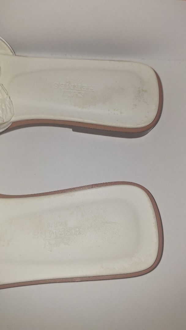 Hermes White Oran Sandals Size 35 (Category: Flats & Sandals) located in Manila. Submitted by decluttering.princess (Listing ID 1467382781, Image 3). Description: - Brand: Hermès - Style: Oran Flat Sandals - Color: White - Size: 35 - Material: Calfskin leather with iconic H cutout - Origin: Made in Italy - Condition: Uppers are clean with minor scuffs; leather soles show normal wear from previous use - Inclusions: Original orange box and two dust