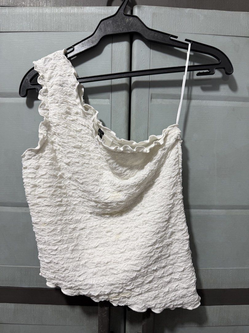 H&M Divided White One-Shoulder Textured Top Size S (Category: Sleeveless) located in Manila. Submitted by aprilled (Listing ID 1467493841, Image 1). Description: - Brand: H&M Divided - Style: One-shoulder top with ruffled neckline trim - Fabric: Textured crinkled fabric - Size: S (fits true to size) - Color: White - Condition: Pre-loved with a couple of small yellowish stains near the front lower section and middle, still lots of wear left.