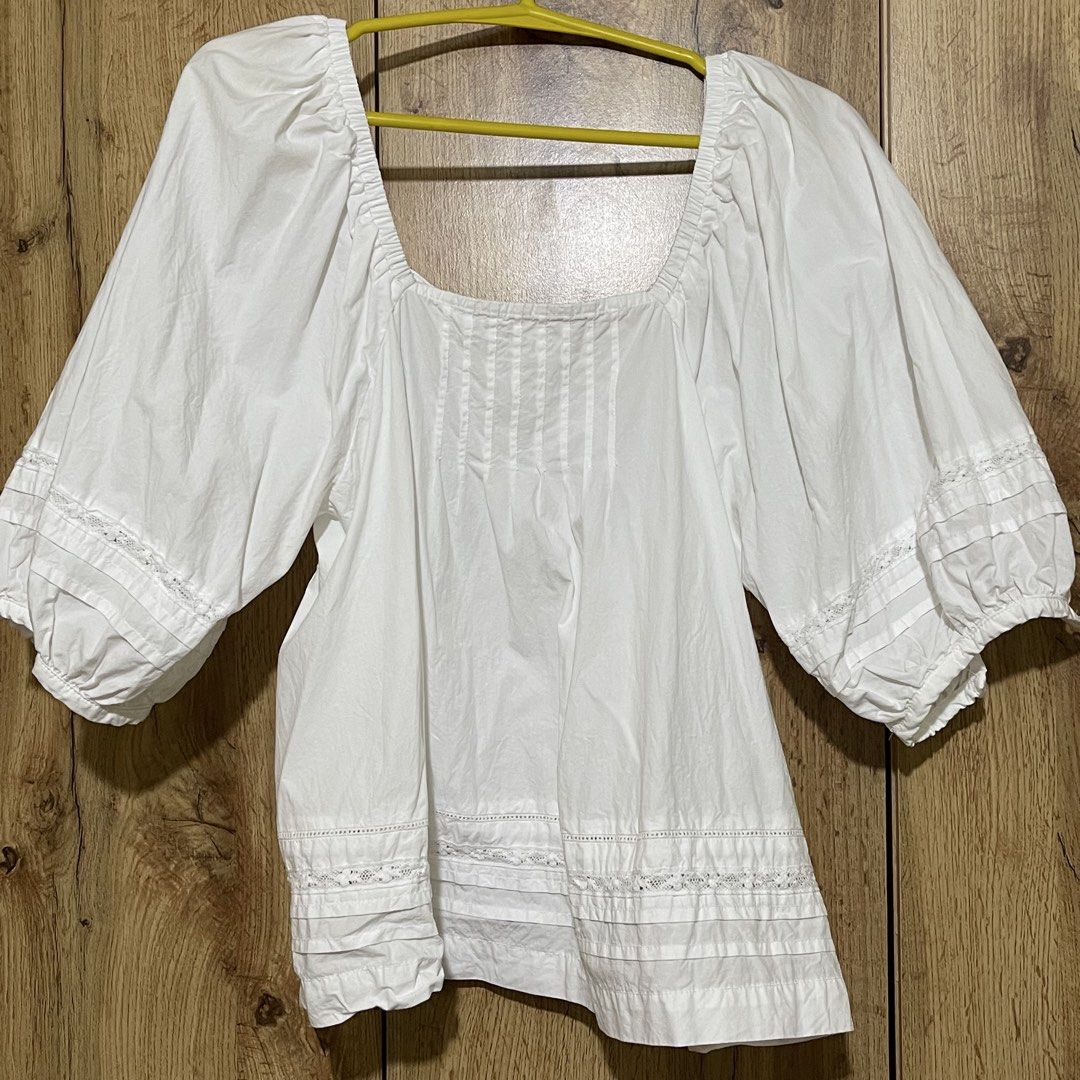 H&M White Square Neck Blouse Size S (Category: Blouses) located in Manila. Submitted by cluttercleanwme (Listing ID 1467581329, Image 2). Description: - Brand: H&M - Size: S - Color: White - Material: Lightweight and breathable cotton - Design: Square neckline with front pintuck pleats - Sleeves: Mid-length balloon sleeves with lace and pleated cuff details - Hem: Matching lace and pleated trim along the bottom - Styling: Versatile piece, great f