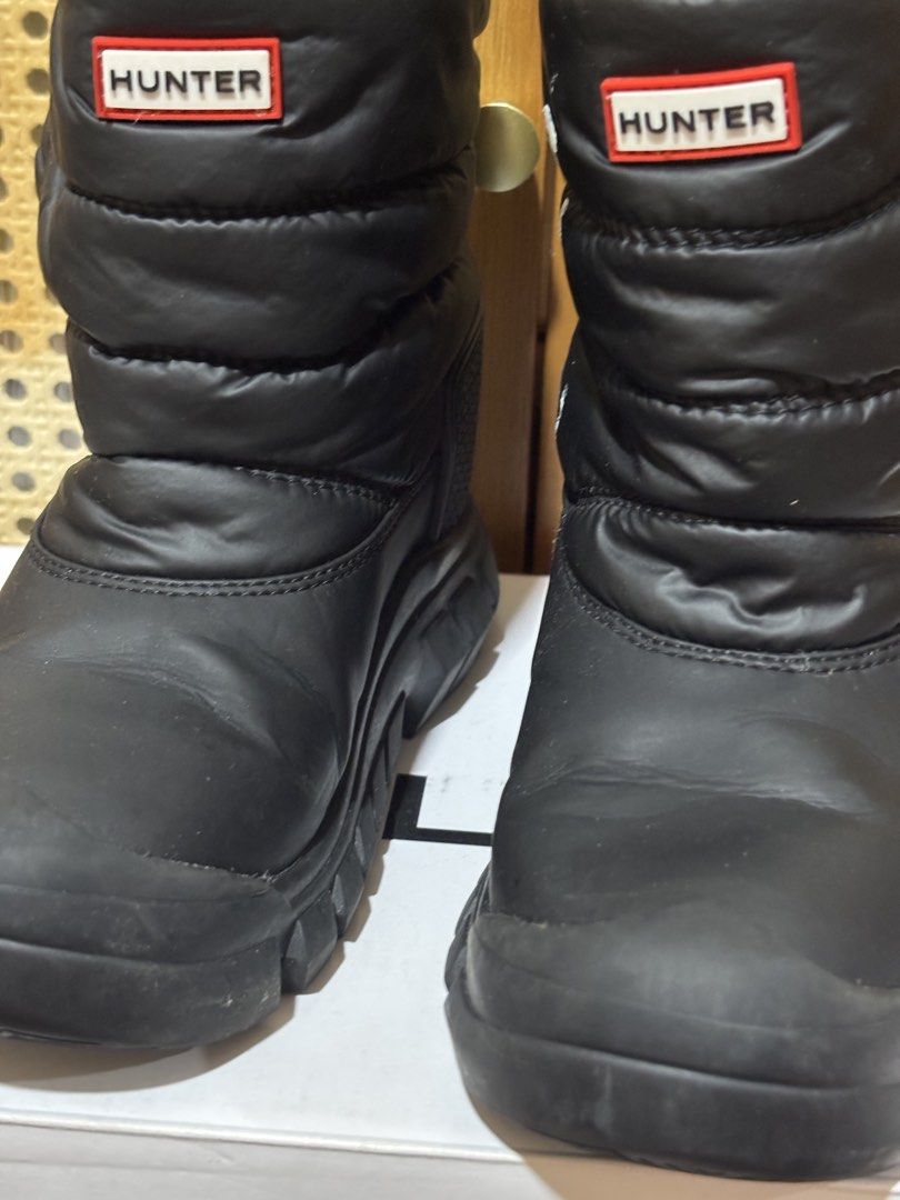 HUNTER Black Snow Boots (Category: Babies & Kids Fashion) located in Manila. Submitted by wardrobeinmnl (Listing ID 1467424740, Image 3). Description: - Brand: Hunter - Style: Black quilted puffer snow boots with iconic red and white logo patch - Interior: Warm and fluffy black fleece lining inside the collar - Soles: Rugged rubber soles ideal for winter weather - Safety: Reflective tabs at the back heels - Flaw Note: There are white paint stains