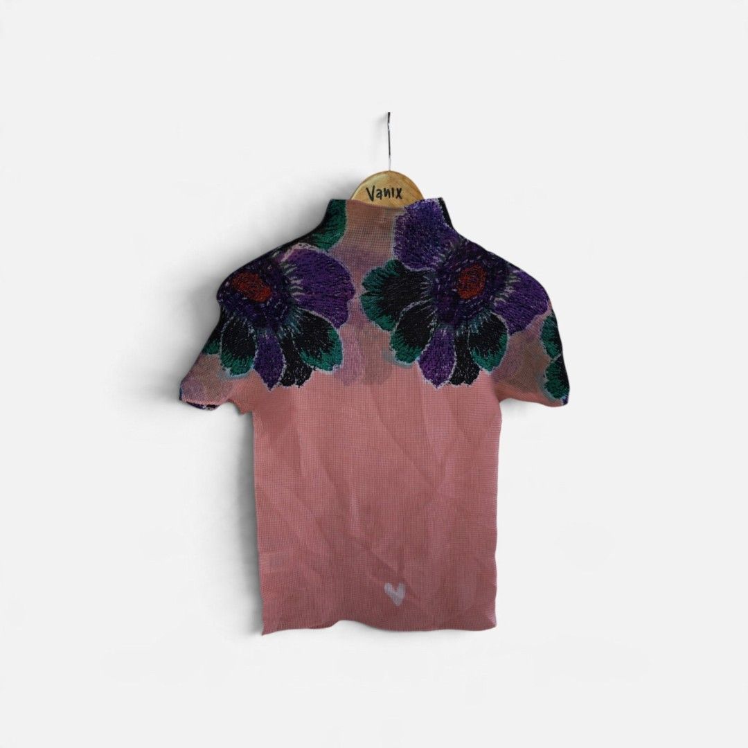 Issey Miyake Pleats Please Top (Category: Blouses) located in Davao. Submitted by thrift2you (Listing ID 1467515715, Image 2). Description: - Pink pleated short sleeve top with a high neck collar - Features a large purple and green floral graphic on the chest and shoulders - Adorable small white heart graphics near the bottom hem - Lightweight, textured fabric with great stretch for all-day comfort - Made in the Philippines from 100% polyester.
