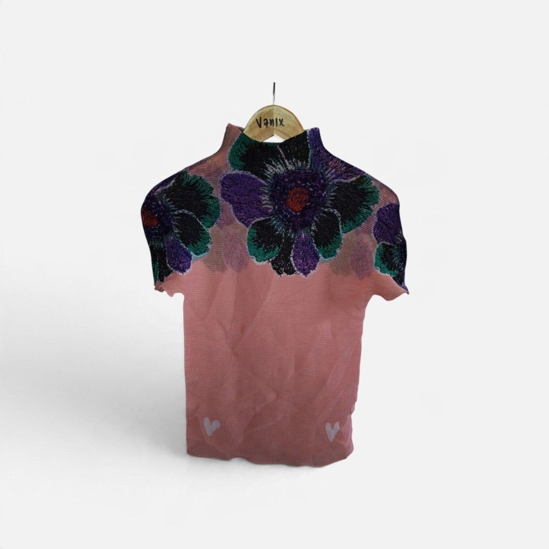 Issey Miyake Pleats Please Top (Category: Blouses) located in Davao. Submitted by thrift2you (Listing ID 1467515715, Image 1). Description: - Pink pleated short sleeve top with a high neck collar - Features a large purple and green floral graphic on the chest and shoulders - Adorable small white heart graphics near the bottom hem - Lightweight, textured fabric with great stretch for all-day comfort - Made in the Philippines from 100% polyester.