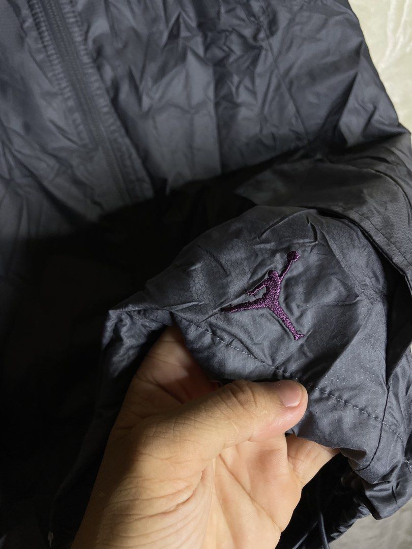 Jordan Jumpman Gray Hooded Windbreaker Jacket Size S (Category: Coats, Jackets and Outerwear) located in Molave. Submitted by charlesthrifter (Listing ID 1467366751, Image 3). Description: - Authentic Jordan windbreaker jacket in size Small - Stylish gray body with an embroidered purple Jumpman logo on the sleeve - Functional hood with a reflective strip down the back for visibility - Breathable printed mesh interior lining - Full zipper closure 