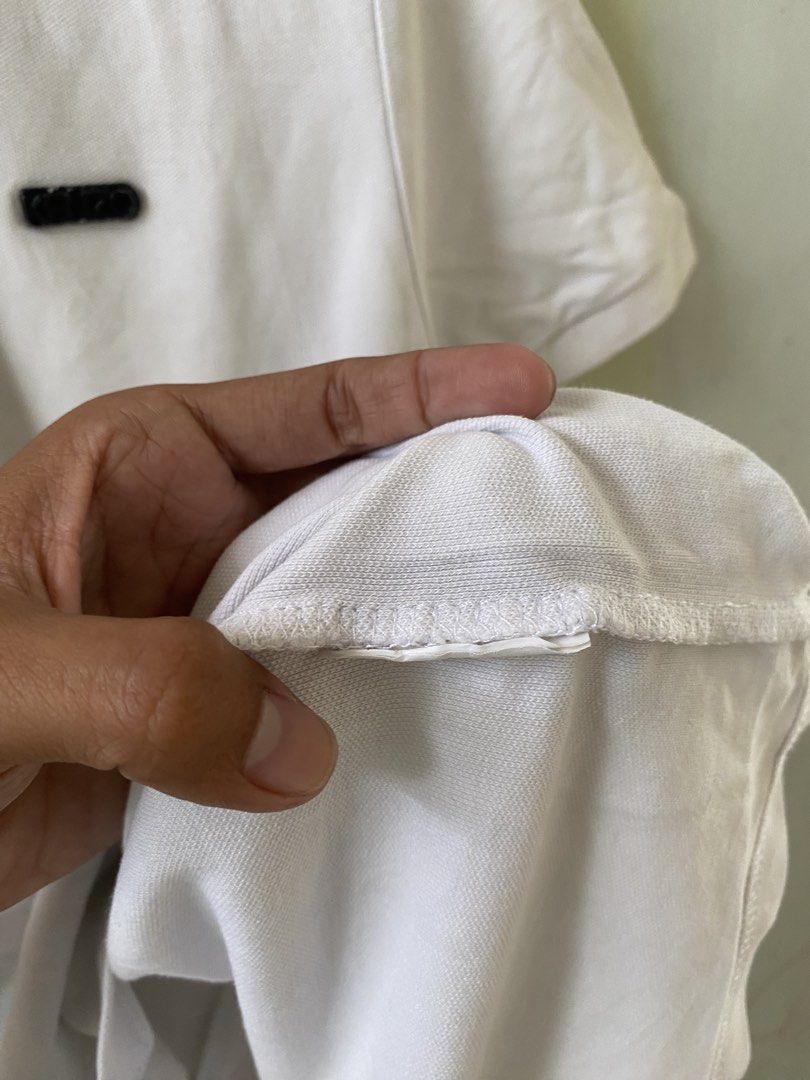 Kenzo Paris White Polo Shirt (Category: Tshirts & Polo Shirts ) located in Pandi. Submitted by nasya_thrift_collection2023 (Listing ID 1467413700, Image 3). Description: - Brand: Kenzo Paris - Color: White - Material: Premium cotton pique fabric - Design: Classic collar with three-button placket, short sleeves - Details: Small black logo patch on left chest, ribbed collar and cuffs - Condition: Excellent, clean neckline label - Shipping: Ships vi
