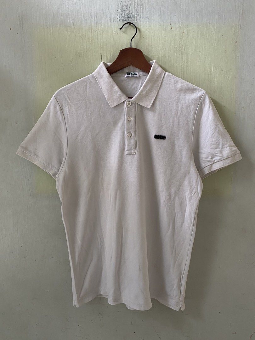 Kenzo Paris White Polo Shirt (Category: Tshirts & Polo Shirts ) located in Pandi. Submitted by nasya_thrift_collection2023 (Listing ID 1467413700, Image 1). Description: - Brand: Kenzo Paris - Color: White - Material: Premium cotton pique fabric - Design: Classic collar with three-button placket, short sleeves - Details: Small black logo patch on left chest, ribbed collar and cuffs - Condition: Excellent, clean neckline label - Shipping: Ships vi
