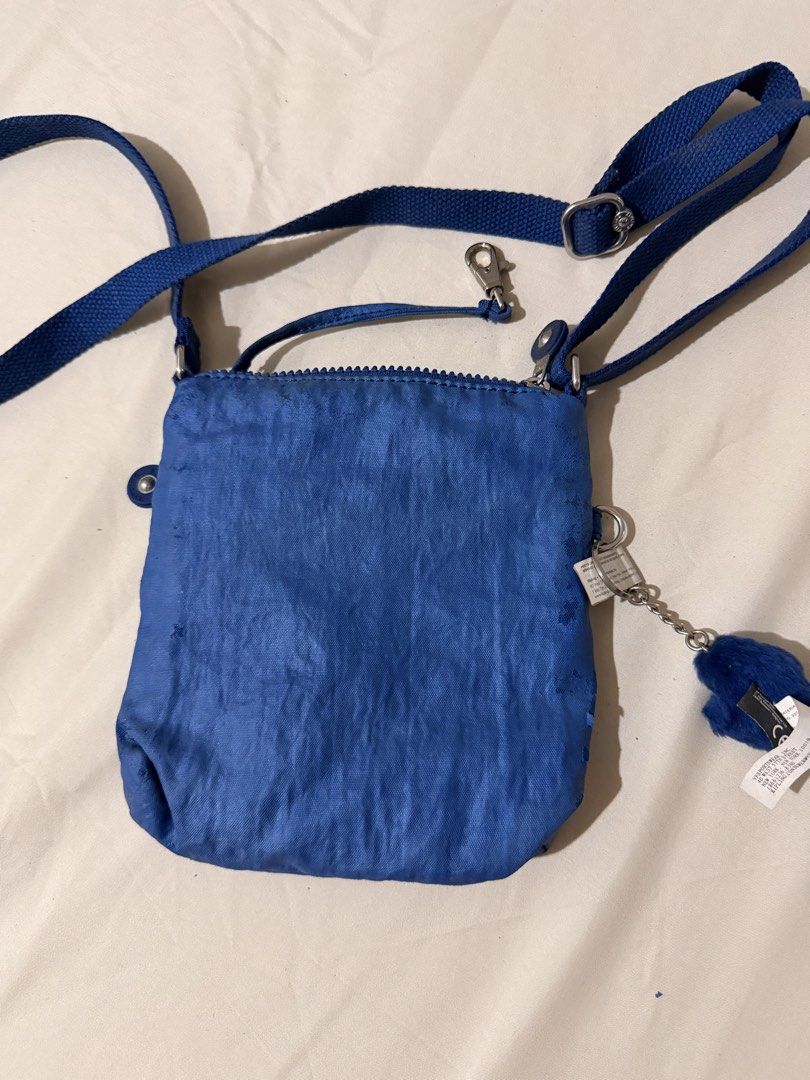 Kipling Blue Crossbody Bag with Monkey Keychain (Category: Cross-body Bags) located in Quezon City. Submitted by mynameismio (Listing ID 1467478141, Image 3). Description: - Brand: Kipling - Color: blue - Material: Signature crinkled nylon fabric with silver-tone hardware - Storage: Main zip compartment and two front zipper pockets - Strap: Adjustable shoulder strap for a custom fit - Inclusion: Matching blue monkey keychain on a metal chain - Co