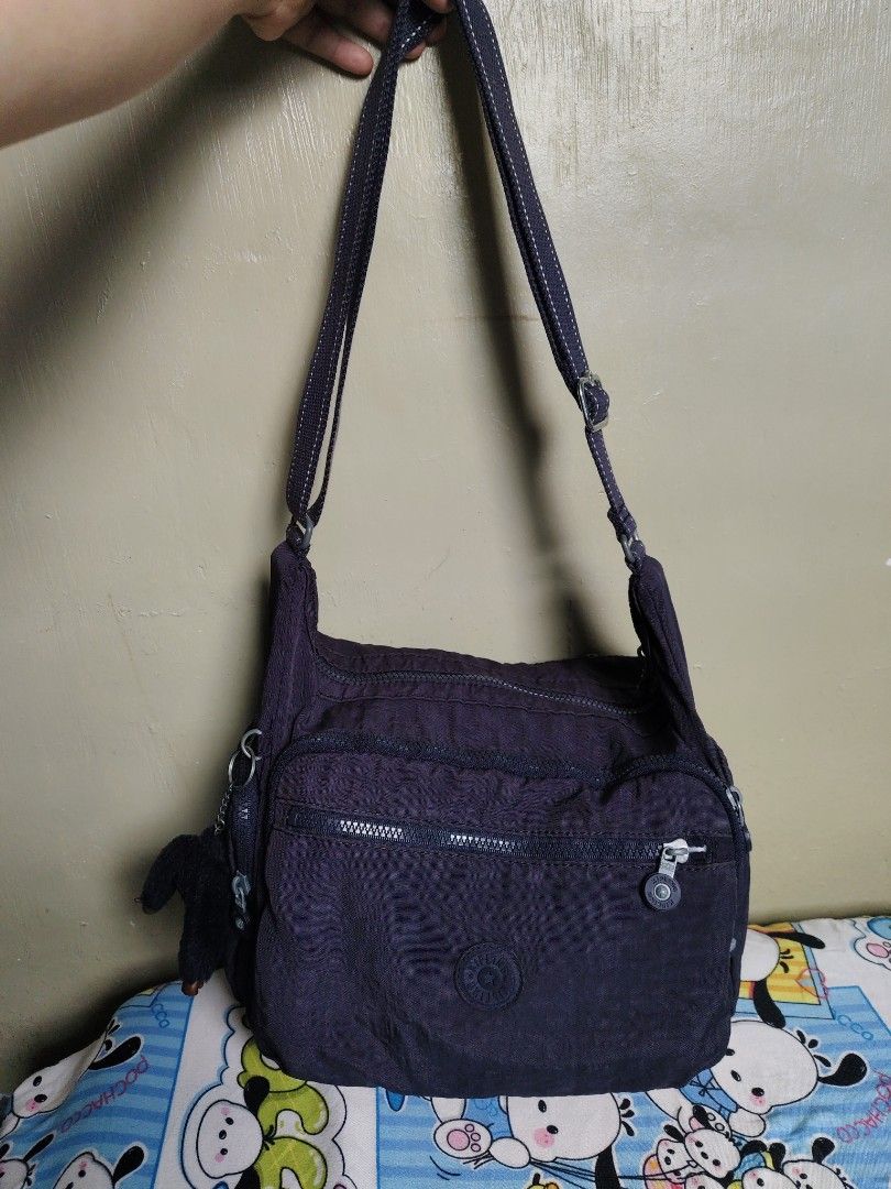 Kipling Purple Shoulder Bag with Monkey Keychain (Category: Shoulder Bags) located in General Mariano Alvarez. Submitted by findsandmoreph (Listing ID 1467367041, Image 1). Description: - Brand: Kipling - Color: Dark Purple - Material: Signature crinkled nylon - Pockets: Multiple front zip compartments - Strap: Adjustable for shoulder or crossbody wear - Inclusion: Original furry monkey keychain - Interior: Stylish patterned fabric lining - Condi