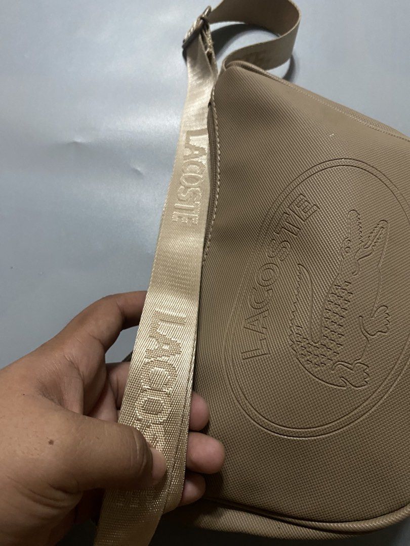 Lacoste Beige Crossbody Shoulder Bag (Category: Cross-body Bags) located in Manila. Submitted by delunakenn94368 (Listing ID 1467515704, Image 3). Description: - Authentic beige Lacoste crossbody bag made of durable textured PVC - Chic embossed crocodile logo on the front - Adjustable branded strap with distinct LACOSTE lettering - Secure top zip closure - Clean interior featuring a zip pocket and Lacoste leather patch tag - Interior tag material