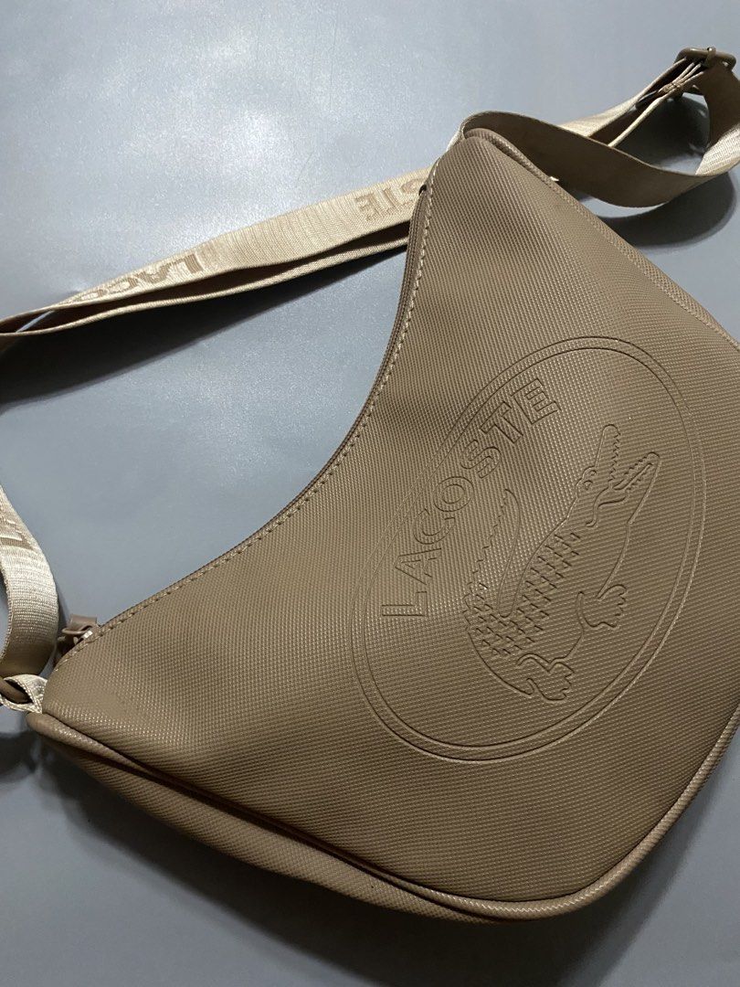 Lacoste Beige Crossbody Shoulder Bag (Category: Cross-body Bags) located in Manila. Submitted by delunakenn94368 (Listing ID 1467515704, Image 2). Description: - Authentic beige Lacoste crossbody bag made of durable textured PVC - Chic embossed crocodile logo on the front - Adjustable branded strap with distinct LACOSTE lettering - Secure top zip closure - Clean interior featuring a zip pocket and Lacoste leather patch tag - Interior tag material
