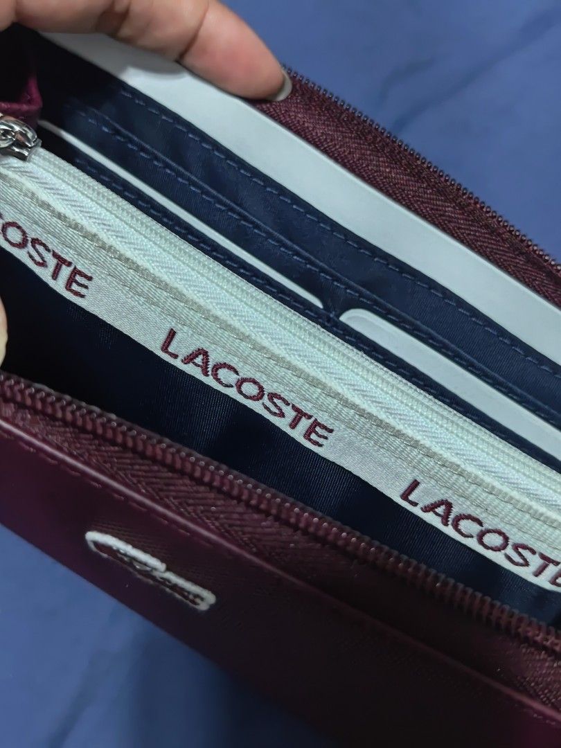Lacoste Burgundy Zip Around Wallet (Category: Wallets & Card holders) located in Pasay City. Submitted by clotheslinemanila (Listing ID 1467530433, Image 2). Description: - Brand: Lacoste (Made in Vietnam) - Condition: Brand new, never used (zipper pull still wrapped in protective paper) - Color: Burgundy exterior with navy blue interior - Material: Textured PVC - Closure: Secure zip-around design - Interior Features: Multiple card slots and an i