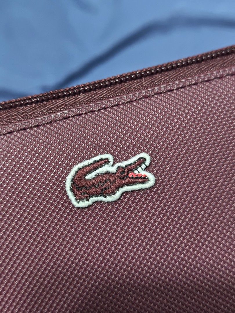 Lacoste Burgundy Zip Around Wallet (Category: Wallets & Card holders) located in Pasay City. Submitted by clotheslinemanila (Listing ID 1467530433, Image 3). Description: - Brand: Lacoste (Made in Vietnam) - Condition: Brand new, never used (zipper pull still wrapped in protective paper) - Color: Burgundy exterior with navy blue interior - Material: Textured PVC - Closure: Secure zip-around design - Interior Features: Multiple card slots and an i