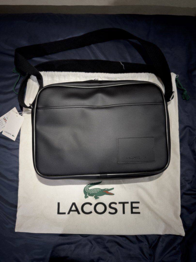 Lacoste Men’s Classic Flight Crossbody Bag (Category: Sling Bags) located in Manila. Submitted by donpd (Listing ID 1467537156, Image 1). Description: Black Lacoste crossbody bag with textured fabric finish. Adjustable black strap, front zip pocket, silver-tone zippers. Inside has multiple slip pockets. Comes with original Lacoste white dust bag and paper tags attached. Clean interior, never used. Only issue is the fraying of leather lining in in