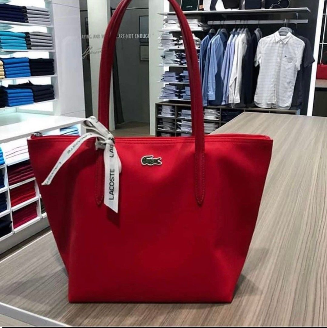 Lacoste Red Tote Bag With Ribbon Accent (Category: Tote Bags) located in Polomolok. Submitted by legadad94559 (Listing ID 1467566016, Image 1). Description: - Authentic Lacoste tote bag in a vibrant red canvas - Brand new with original retail tags attached - Secure top zipper closure - Sturdy shoulder straps still wrapped in protective plastic - Elegant branded ribbon tied neatly on the front handle - Spacious interior featuring a zippered pocket