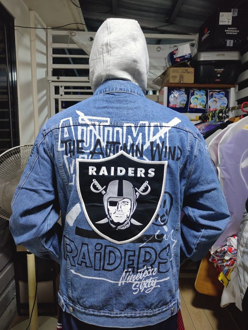 Las Vegas Raiders NFL Denim Jacket (Category: Coats, Jackets and Outerwear) located in Pandi. Submitted by yanyan_apparel.store08 (Listing ID 1467374008, Image 2). Description: - Style: Blue denim jacket with bold Las Vegas Raiders graphics - Details: Large embroidered Raiders shield patch on the back - Text Accents: Features 'The Autumn Wind', '1960', and 'Pillaging Just For Fun' - Design: Classic button-up closure - Pockets: Two chest pockets a
