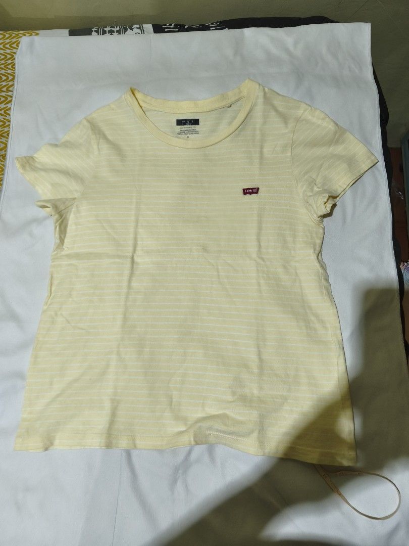 Levi's Yellow Striped T-Shirt (Category: Shirts) located in Quezon City. Submitted by tintinarms (Listing ID 1467521884, Image 1). Description: - Brand: Levi's - Style: Short sleeve crew neck tee with all-over white stripes - Color: Light yellow - Size: Medium (Made in Bangladesh) - Measurement: ~18 inches pit to pit (flat lay) - Details: Small red Levi's logo patch on the chest, soft and clean cotton fabric - Condition: Great casual basic for ev