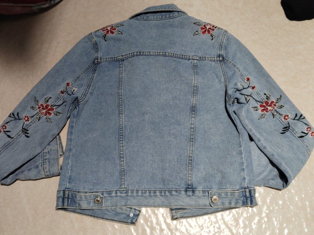 Light wash floral embroidered denim jacket (Category: Coats, Jackets and Outerwear) located in Manila. Submitted by az272019 (Listing ID 1467602855, Image 2). Description: - Style: Classic denim trucker jacket in a light wash blue - Design: Beautiful intricate floral embroidery on the chest, sleeves, and back - Details: Button-up front, collar, chest pockets, and detailed stitching throughout - Versatility: Great layering piece for cooler weather