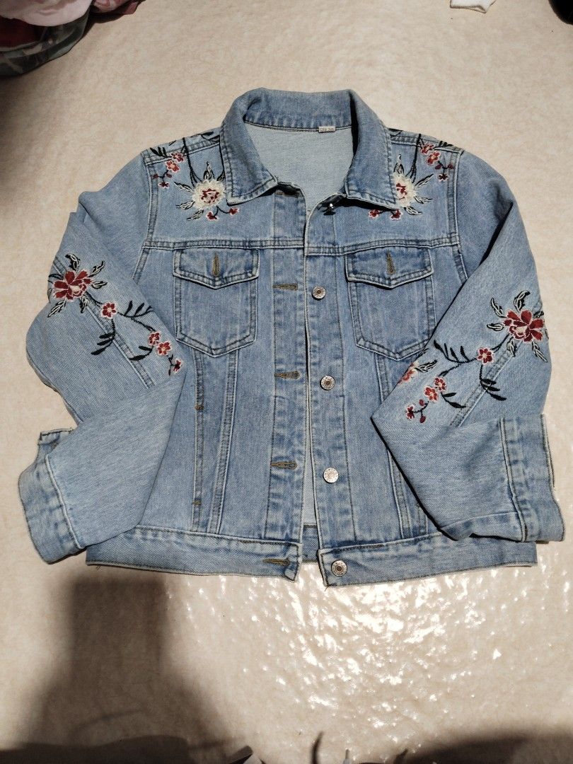 Light wash floral embroidered denim jacket (Category: Coats, Jackets and Outerwear) located in Manila. Submitted by az272019 (Listing ID 1467602855, Image 1). Description: - Style: Classic denim trucker jacket in a light wash blue - Design: Beautiful intricate floral embroidery on the chest, sleeves, and back - Details: Button-up front, collar, chest pockets, and detailed stitching throughout - Versatility: Great layering piece for cooler weather