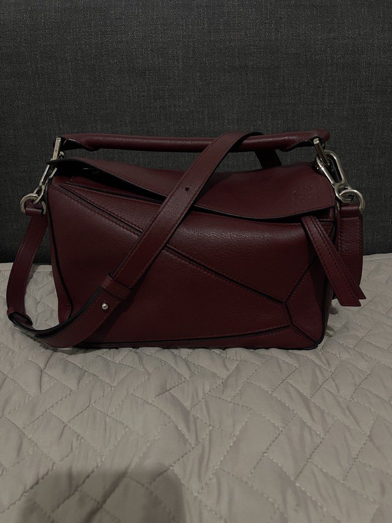Loewe Puzzle Bag Burgundy Leather (Category: Luxury Bags & Wallets) located in Cavite. Submitted by cheetozjalapeeeeno (Listing ID 1467476271, Image 1). Description: Burgundy Loewe Puzzle bag in classic calfskin. Geometric panel design with silver-tone hardware. Removable shoulder strap with Anagram dice detail. Top handle and rear zip pocket. Cream herringbone canvas lining inside. Interior leather tag stamped Loewe Made in Spain. Structured sha