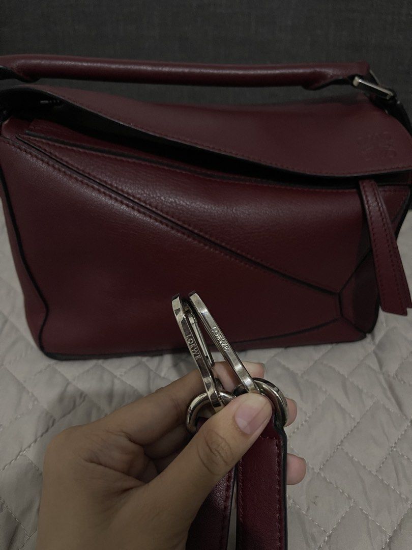 Loewe Puzzle Bag Burgundy Leather (Category: Luxury Bags & Wallets) located in Cavite. Submitted by cheetozjalapeeeeno (Listing ID 1467476271, Image 3). Description: Burgundy Loewe Puzzle bag in classic calfskin. Geometric panel design with silver-tone hardware. Removable shoulder strap with Anagram dice detail. Top handle and rear zip pocket. Cream herringbone canvas lining inside. Interior leather tag stamped Loewe Made in Spain. Structured sha