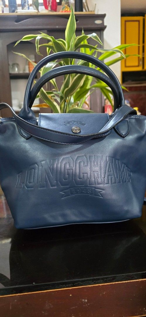 Longchamp Navy Blue Leather Handbag (Category: Luxury Bags & Wallets) located in Antipolo. Submitted by happinessprelove (Listing ID 1467382667, Image 1). Description: - Brand: Longchamp - Color: Navy Blue - Material: Premium Leather - Style: Handbag / Travel Tote (Model: 1624746168) - Origin: Made in France - Exterior: Large embossed logo lettering on front, dual carry handles with snap button flap closure - Interior: Secure zipper top opening w