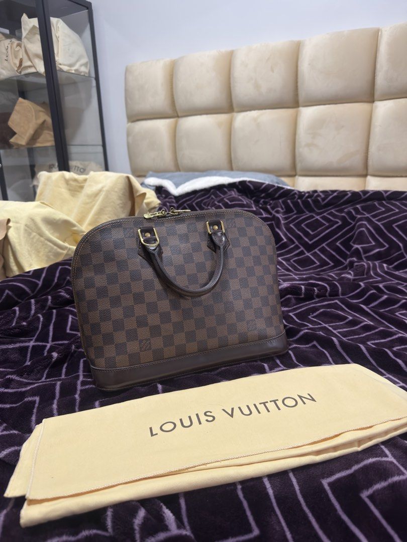 Louis Vuitton Damier Ebene Alma PM Handbag (Category: Luxury Bags & Wallets) located in Caloocan City. Submitted by kimmndza_176 (Listing ID 1467512459, Image 2). Description: - Brand: Louis Vuitton - Model: Alma PM - Material: Classic Damier Ebene canvas with brown leather trim - Hardware: Gold-tone - Closure: Double zip closure - Shape: Structured dome silhouette with a flat base - Inclusions: Original yellow LV dust bag - Condition: Great ever