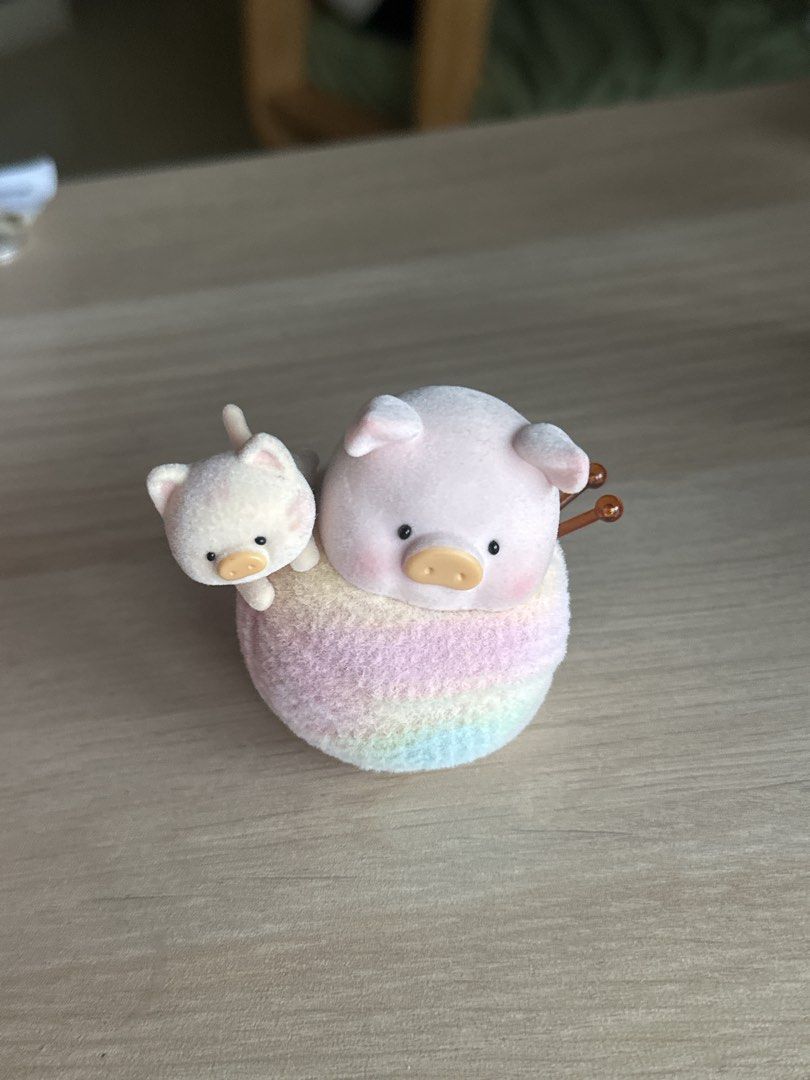 Lulu the Pig (Category: Designer & Blind Box Toys) located in Quezon City. Submitted by shopfinesse (Listing ID 1467397784, Image 2). Description: - Adorable flocked figurine set with a large pink pig and tiny white kitten - Animals are sitting together on a pastel rainbow ball of yarn with knitting needles - Features a smooth, soft velvety texture - Perfect as cute desk decor or shelf ornament.