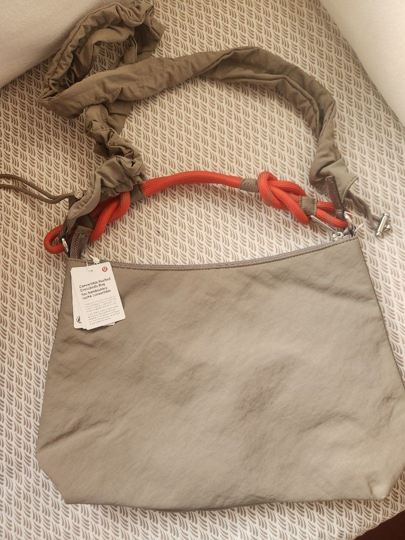 Lululemon Convertible Ruched Crossbody Bag (Category: Cross-body Bags) located in Makati City. Submitted by mikamix (Listing ID 1467601376, Image 2). Description: - Brand: Lululemon - Style: Convertible ruched crossbody bag - Color: Muted green with a bright orange knotted rope strap - Hardware: Silver-tone with top zipper closure - Interior: Grey fabric lining with convenient zip and slip pockets - Condition: Brand new, never used, with original