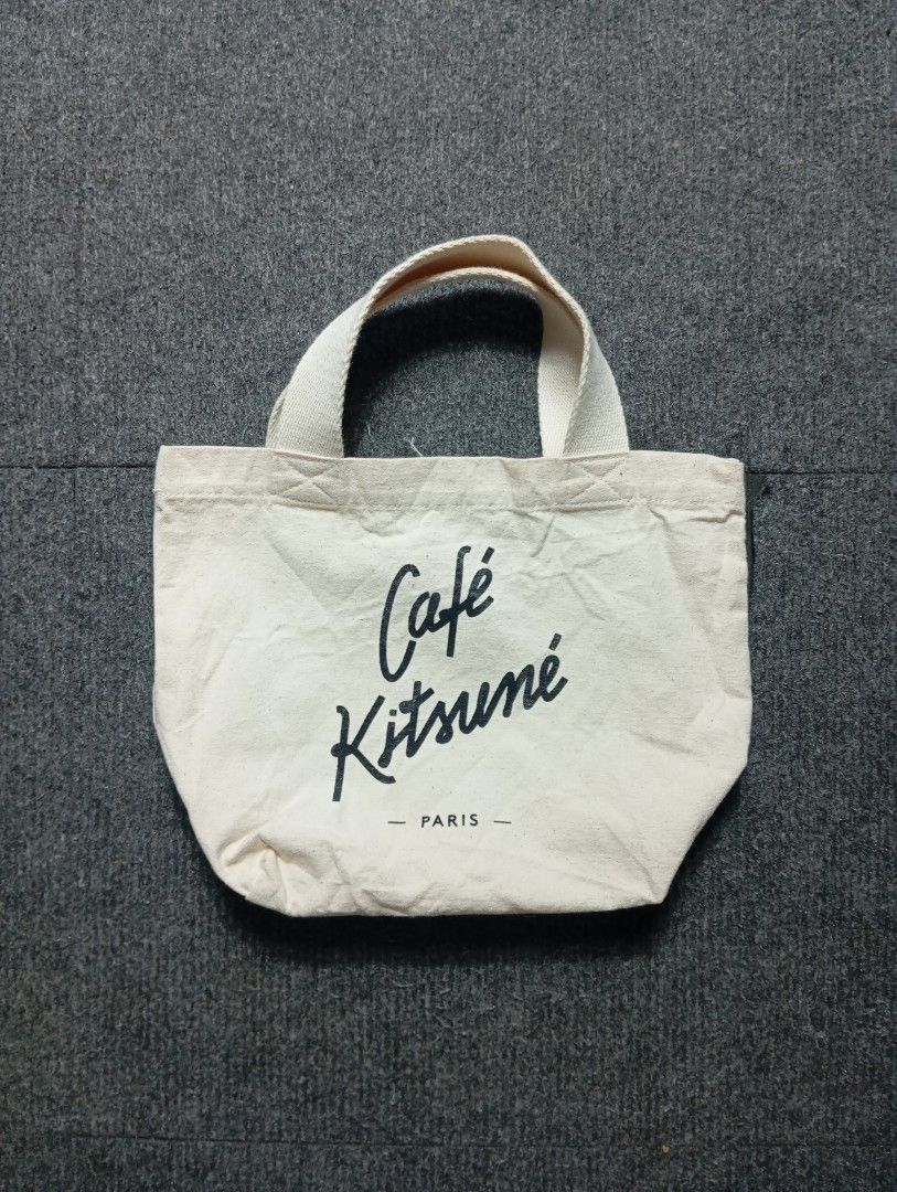 Maison Kitsuné Paris Canvas Tote Bag (Category: Tote Bags) located in Ligao. Submitted by merjudioma64633 (Listing ID 1467365949, Image 1). Description: - Brand: Café Kitsuné - Color: Off-white - Material: Durable canvas - Design: Signature script logo on front, open top with double top handles - Interior: Includes brand label tag and product care tag - Origin: Made in Korea - Size: Standard everyday size for daily essentials - Condition: .