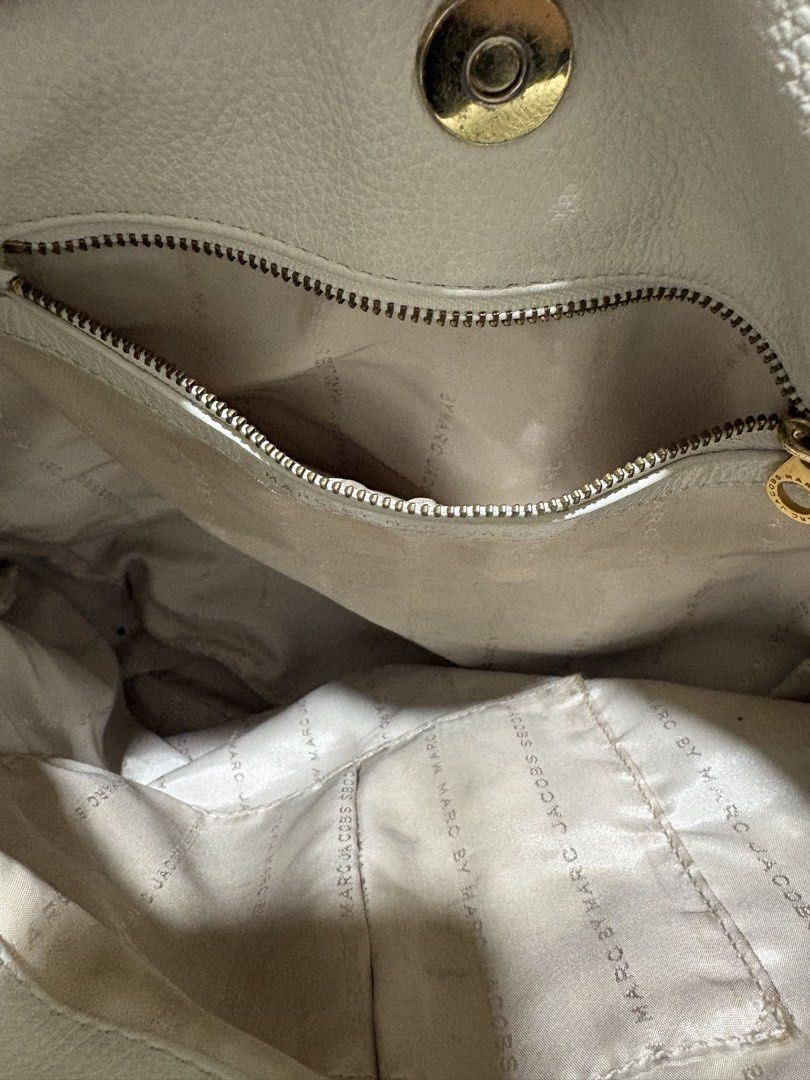 Marc by Marc Jacobs White Leather Shoulder Bag (Category: Luxury Bags & Wallets) located in Pasig City. Submitted by anenri (Listing ID 1467410051, Image 3). Description: - Brand: Marc by Marc Jacobs - Material: White textured leather - Hardware: Gold-tone with front metal logo plaque - Straps: Top handle plus an adjustable and detachable shoulder strap - Closure: Secure magnetic top snap - Interior: Monogram fabric lining with a convenient zip p
