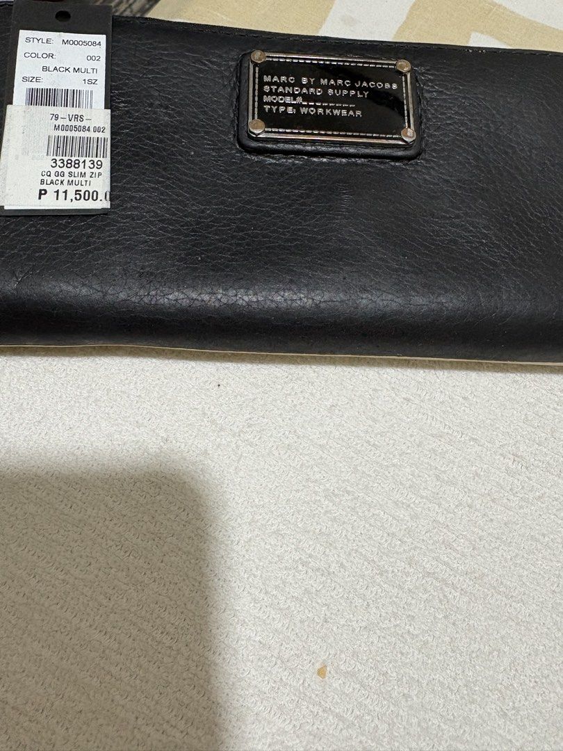 Marc Jacobs M0005084 Black Multi Zip Wallet (Category: Wallets & Card holders) located in Pasig City. Submitted by anenri (Listing ID 1467430694, Image 2). Description: Marc Jacobs zip around wallet in black multi colorway. Style code M0005084. Inside has multiple card slots, zip coin pocket, and black-and-white patterned lining. Tag still attached showing color 002. Smooth leather exterior construction with silver-tone hardware..