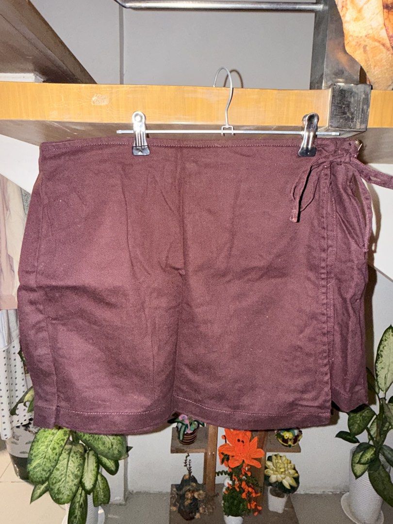 Maroon denim skort with side tie (Category: Skirts) located in Manila. Submitted by clalala.fire (Listing ID 1467526925, Image 1). Description: - Color: Deep maroon (rich autumn shade) - Design: Wrap style with a chic side tie on the right hip and structured back paneling for a flattering fit - Fabric: Textured, linen-look material with clean hem stitching - Styling: Perfect to pair with basic tees or blouses for casual days out - Condition: Bran