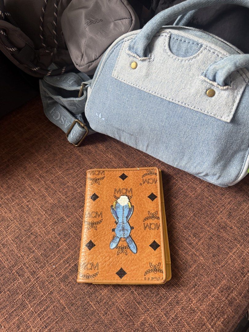 MCM Visetos Rabbit Passport Holder in Cognac. (Category: Luxury Bags & Wallets) located in Bayombong. Submitted by nica7 (Listing ID 1467369344, Image 2). Description: In good condition MCM Visetos Rabbit Passport Holder in Cognac. Product Details • Material: Coated canvas with Visetos monogram and leather trim • Color: Cognac brown exterior with a bright yellow/gold interior • Design Feature: Cartoon blue rabbit graphic printed on the front • In