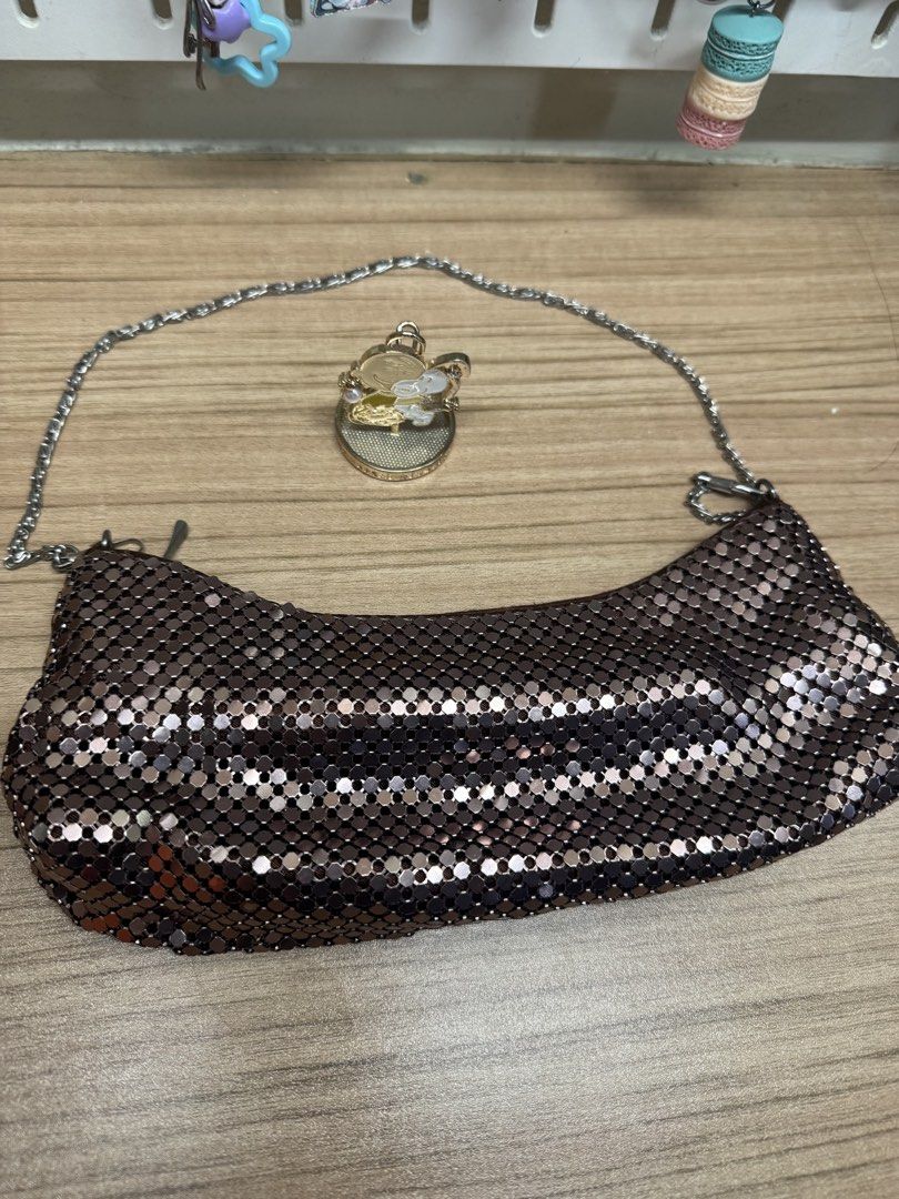 Metallic mesh shoulder bag with chain strap (Category: Shoulder Bags) located in Manila. Submitted by xenasales (Listing ID 1467372745, Image 1). Description: - Sparkly metallic mesh shoulder bag in a chic bronze/dark brown tone - Trendy curved baguette shape with a slim silver-tone chain strap - Includes an adorable matching circular charm with a character design - Clean interior lining - Perfect statement piece for night outs, parties, and even