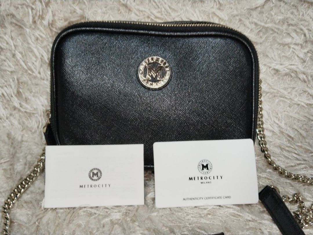 Metrocity Black Crossbody Bag with Chain Strap (Category: Cross-body Bags) located in Caloocan City. Submitted by jezel07 (Listing ID 1467547541, Image 2). Description: - Brand: Metrocity - Material: Black textured leather - Hardware: Gold-tone with signature M logo medallion - Closure: Top zipper closure - Strap: Chain strap with comfortable leather shoulder guard - Inclusions: Original authenticity certificate card (Style: MF75517) and packagin