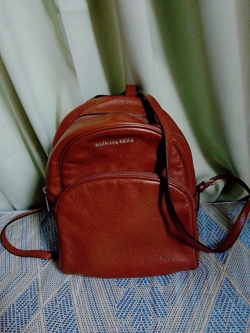 Michael Kors Brown Leather Backpack (Category: Backpacks) located in Bulacan. Submitted by ann_chua84 (Listing ID 1467443825, Image 1). Description: - Brand: Michael Kors - Material: Brown pebble leather with gold-tone hardware - Compartments: Main zip compartment, front zip pocket, and interior zip pocket - Straps: Adjustable shoulder straps and top grab handle - Condition: Clean interior and exterior with minor normal storageccreases. and a lit