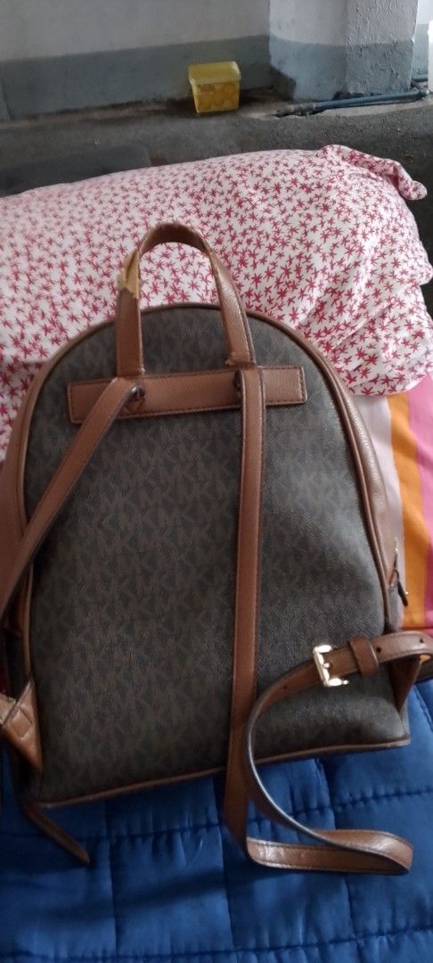Michael Kors Brown MK Monogram Backpack (Category: Backpacks) located in Caloocan City. Submitted by nobleflower_4c42cc (Listing ID 1467412570, Image 3). Description: - Brand: Michael Kors - Design: Classic brown MK monogram print with tan leather trim and gold-tone hardware - Compartments: Secure double zip main closure and convenient front zippered pocket - Carry Options: Adjustable shoulder straps and top carry handle - Condition: Good overall