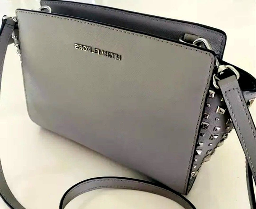 Michael Kors Grey Studded Crossbody Bag (Category: Cross-body Bags) located in Manila. Submitted by lene48 (Listing ID 1467403541, Image 1). Description: - Brand: Michael Kors - Color: Grey - Material: Genuine Leather - Hardware: Silver - Features: Studded gusset details, adjustable strap, zip top closure - Interior: Clean branded fabric lining with slip and zip pockets wuth fkaw last pic. Medium size - Authenticity: QR code tag inside.