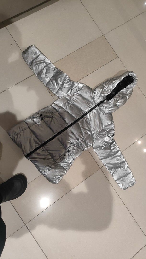 Michael Kors Silver Puffer Jacket Hooded (Category: Coats, Jackets and Outerwear) located in Caloocan City. Submitted by joshuadyogi0122 (Listing ID 1467537692, Image 2). Description: Michael Kors metallic silver puffer jacket. Zip-up front with attached hood. Quilted design keeps warmth in. Two front pockets with snap buttons featuring engraved branding. Signature round MK logo plaque on the left sleeve. Shell is 100 percent nylon, filling and l