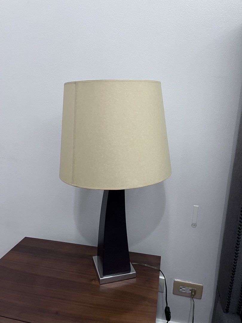 Modern Table Lamp with Curved Black Base and Beige Shade (Category: Lighting) located in Manila. Submitted by this_is_my_closet (Listing ID 1467525045, Image 2). Description: Table lamp featuring a curved black textured body, chrome base plate, and large beige tapered shade. Includes a spiral compact fluorescent bulb. Cord has an inline switch and standard plug. Total height sits around two feet. Neutral tones fit bedside tables or living room de