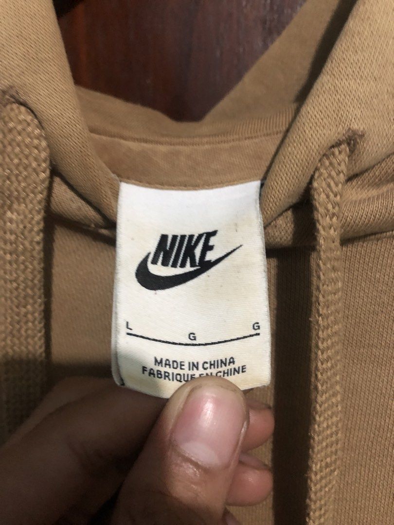 Nike Beige Hoodie (Category: Hoodies) located in Quezon City. Submitted by yeahsource222 (Listing ID 1467529627, Image 3). Description: - Brand: Nike - Style: Classic pullover hoodie with front kangaroo pocket and adjustable drawstring hood - Color: Tan with white embroidered logo on the chest - Size: Large - Condition: Minor wear on ribbed cuffs and hem, with small reddish marks near the neckline - Perfect for: Comfortable everyday streetwear.