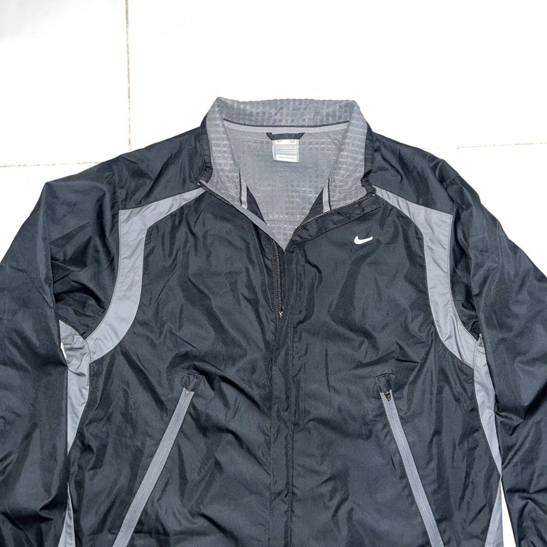Nike Clima-FIT technical windbreaker track jacket (Category: Coats, Jackets and Outerwear) located in Puerto Princesa. Submitted by sydneyavouz (Listing ID 1467514084, Image 3). Description: - Brand: Nike - Color: Black with grey accent panels - Size: Medium (tag inside collar) - Features: Zip-up closure, high collar with textured grey lining, and zippered front pockets - Branding: White Nike swoosh logo on the right chest - Condition: Excellent,