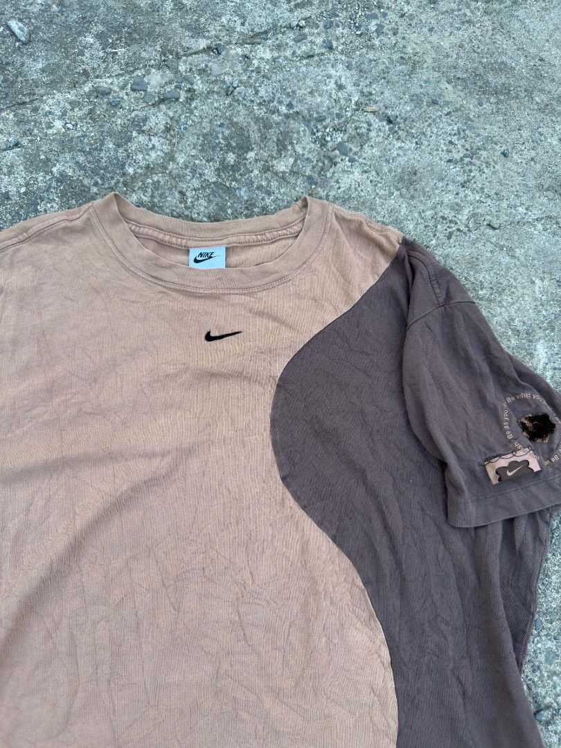 Nike Two-Tone Brown T-Shirt (Category: Tshirts & Polo Shirts ) located in Urdaneta. Submitted by goldeneagle-e662 (Listing ID 1467378640, Image 2). Description: - Brand: Nike - Color: Brown and tan colorblock with faded wash - Material: 100% cotton (Made in Turkey tag) - Design: Short sleeves, crew neckline, small embroidered swoosh on chest - Flaws/Condition: Noticeable hole and distressed patch detail on the left sleeve.