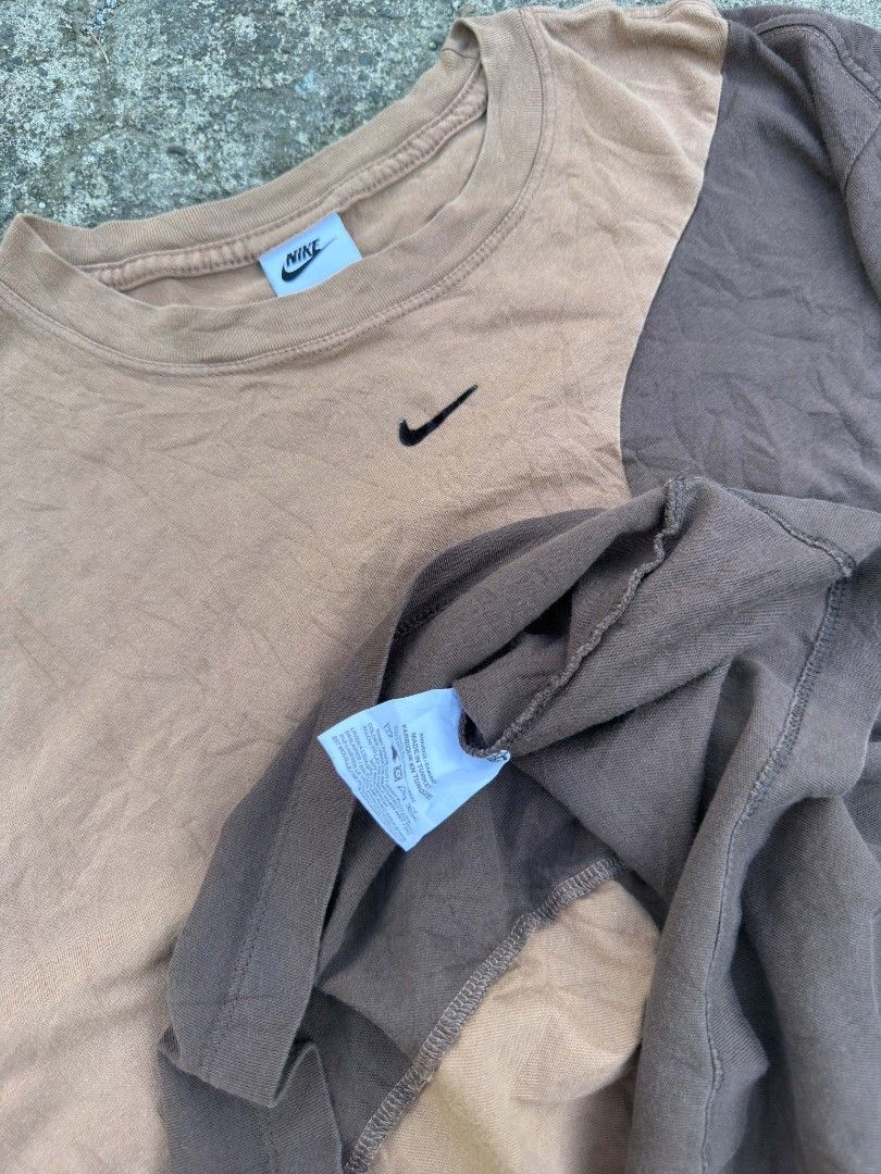 Nike Two-Tone Brown T-Shirt (Category: Tshirts & Polo Shirts ) located in Urdaneta. Submitted by goldeneagle-e662 (Listing ID 1467378640, Image 3). Description: - Brand: Nike - Color: Brown and tan colorblock with faded wash - Material: 100% cotton (Made in Turkey tag) - Design: Short sleeves, crew neckline, small embroidered swoosh on chest - Flaws/Condition: Noticeable hole and distressed patch detail on the left sleeve.