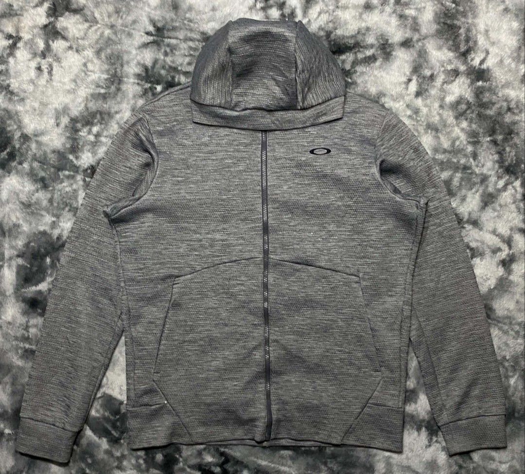 Oakley Performance Fit Grey Zip Hoodie (Category: Coats, Jackets and Outerwear) located in Sorsogon. Submitted by johnmichae69459 (Listing ID 1467513844, Image 1). Description: - Brand: Oakley - Color: Grey with textured fabric pattern - Size: US/EU Medium / Japan Large - 23 width - 27 lenght - Material: 100% Polyester - Features: Embroidered chest logo, high neck hood, smooth YKK zipper, and front pockets - Origin: Made in Myanmar - Condition: E