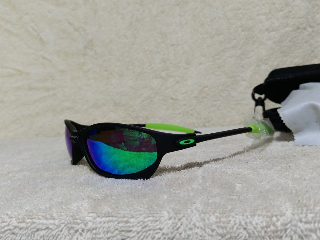 Oakley Sunglasses Black Neon Green Frame (Category: Sunglasses & Eyewear) located in Cavite. Submitted by navias (Listing ID 1467549400, Image 3). Description: Origin:UAE - Brand: Oakley - Colorway: Matte black frame with neon green accents on the arms - Lenses: Vibrant reflective lenses with blue and green hues - Origin: Made in Italy (text printed inside temple) - Condition: Excellent, one arm is still wrapped in original protective plastic - I