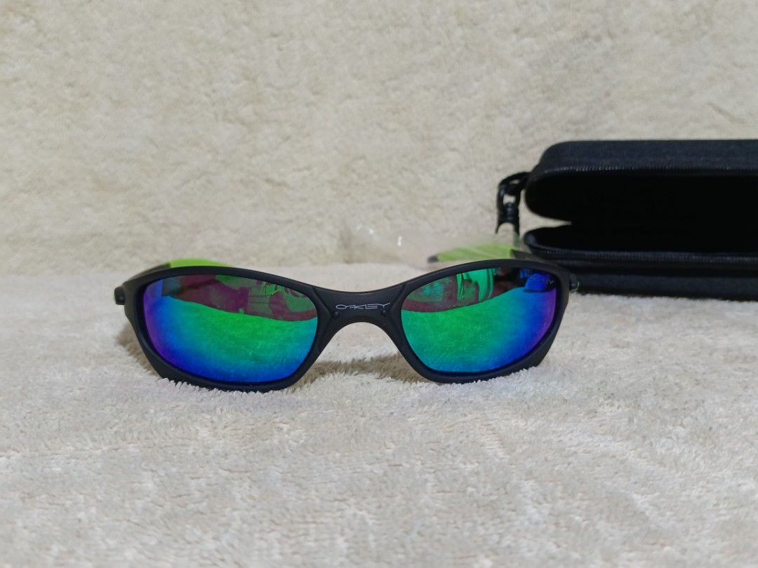 Oakley Sunglasses Black Neon Green Frame (Category: Sunglasses & Eyewear) located in Cavite. Submitted by navias (Listing ID 1467549400, Image 1). Description: Origin:UAE - Brand: Oakley - Colorway: Matte black frame with neon green accents on the arms - Lenses: Vibrant reflective lenses with blue and green hues - Origin: Made in Italy (text printed inside temple) - Condition: Excellent, one arm is still wrapped in original protective plastic - I