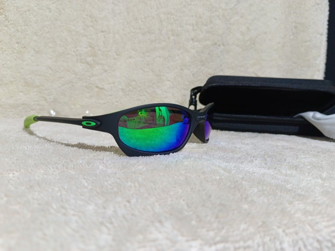 Oakley Sunglasses Black Neon Green Frame (Category: Sunglasses & Eyewear) located in Cavite. Submitted by navias (Listing ID 1467549400, Image 2). Description: Origin:UAE - Brand: Oakley - Colorway: Matte black frame with neon green accents on the arms - Lenses: Vibrant reflective lenses with blue and green hues - Origin: Made in Italy (text printed inside temple) - Condition: Excellent, one arm is still wrapped in original protective plastic - I